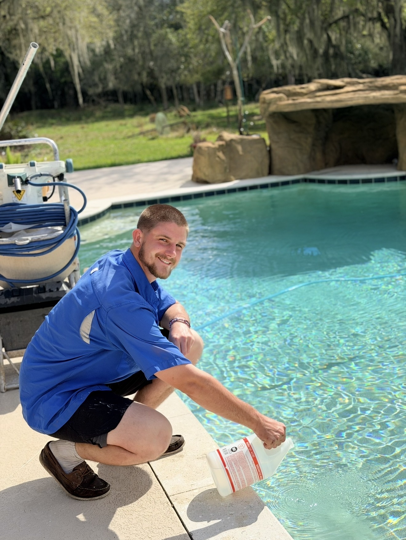 Jediah adding pool chemicals to a sparkling blue pool — Exalt Pools service